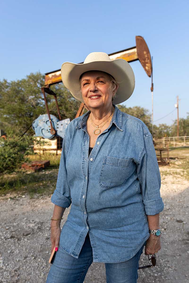 Woman in denim shirt and jeans standing in front of an oil pumper